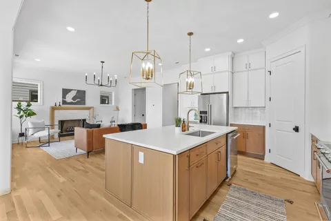 a kitchen with a stove a sink dishwasher a refrigerator oven and white cabinets with wooden floor