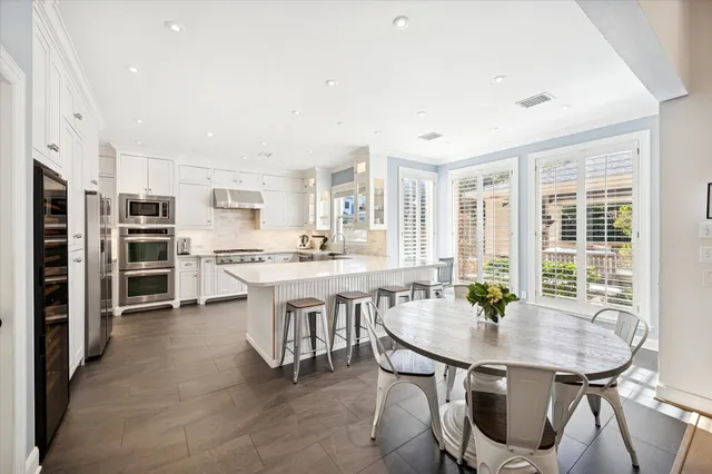 a kitchen with stainless steel appliances a dining table chairs and white cabinets