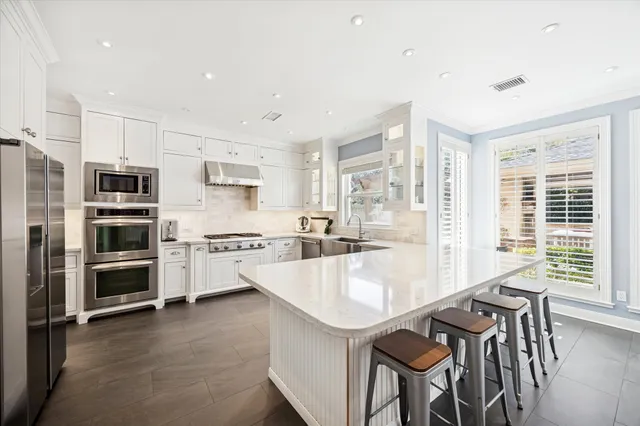 a large kitchen with kitchen island a large window and stainless steel appliances
