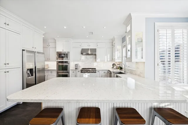 a large kitchen with kitchen island a large counter top space a sink stainless steel appliances and cabinets