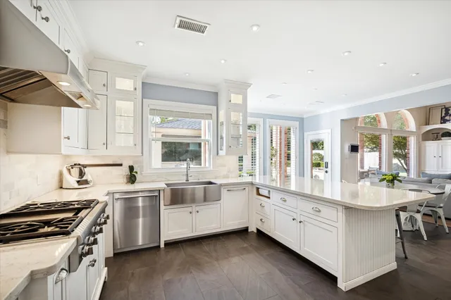 a large white kitchen with stainless steel appliances a sink a stove and a window