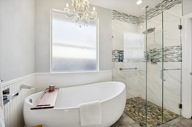 a bathroom with a tub a window and a shower