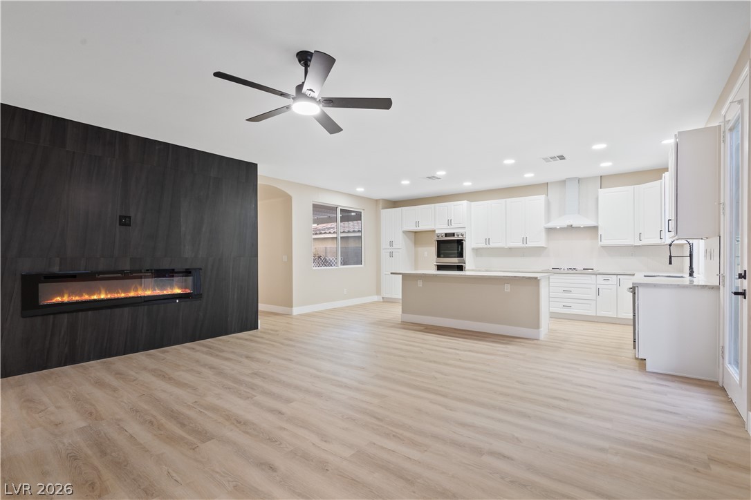 1662 Ravanusa Drive Henderson, NV 89052 - Photo 10 of 74 An open-concept living area features an electric fireplace and a modern kitchen with a large island.