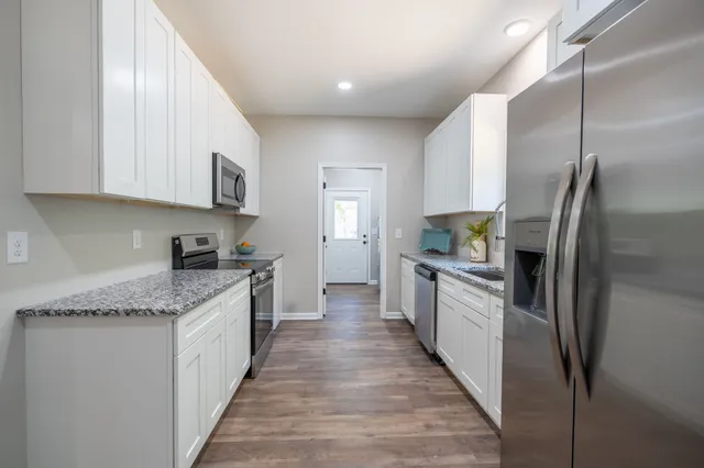 a large kitchen with stainless steel appliances granite countertop a lot of counter space and wooden floor