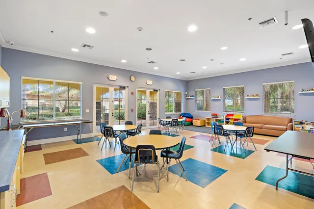 a room with lots of tables a large window and chairs