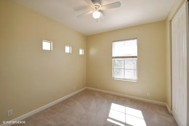 an empty room with a window and a fan