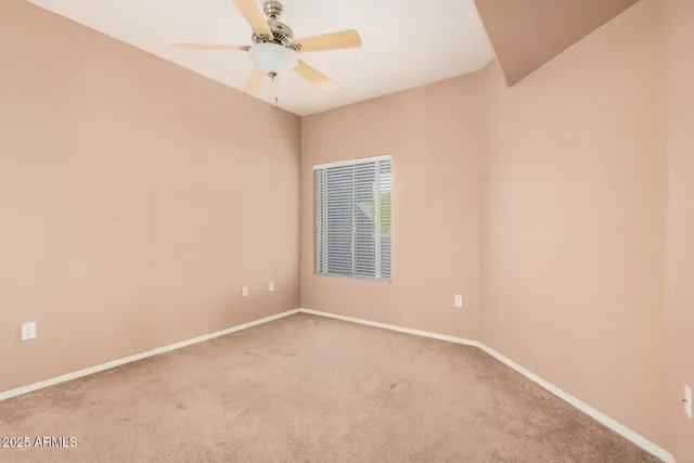 an empty room with a window and ceiling fan