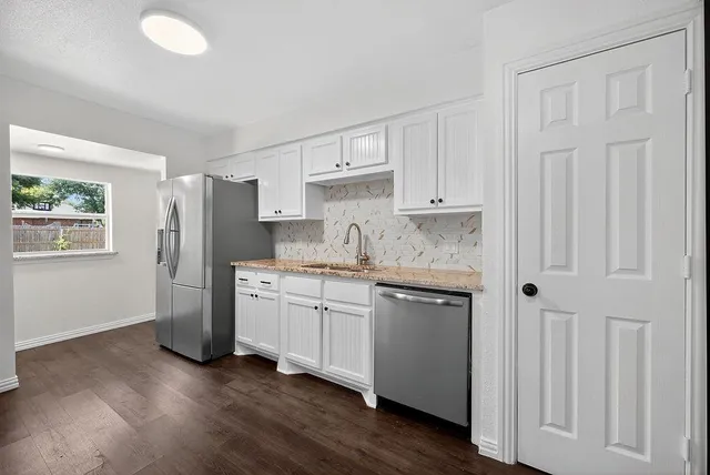 a kitchen with stainless steel appliances granite countertop a refrigerator sink and white cabinets