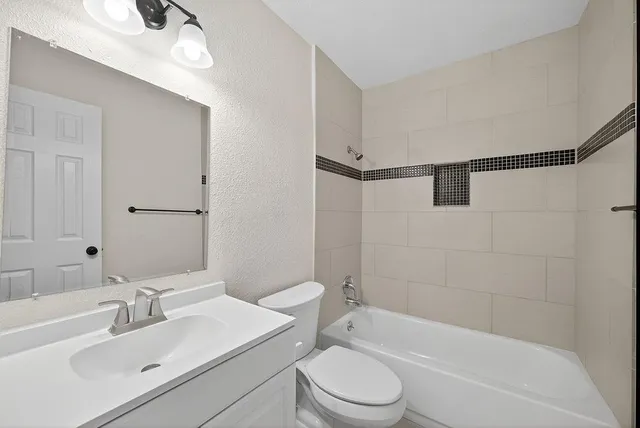 a bathroom with a bathtub shower sink vanity mirror and toilet