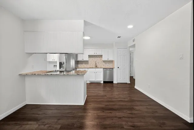 a kitchen with a refrigerator and white cabinets