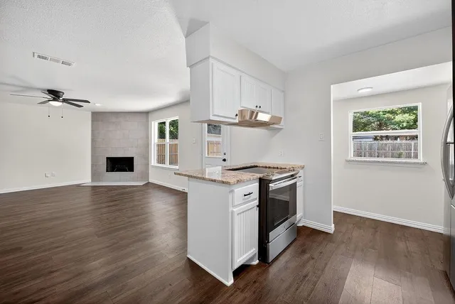 a kitchen with granite countertop a stove and a wooden floors