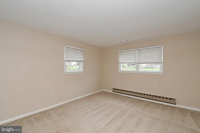a view of an empty room with closet and a window