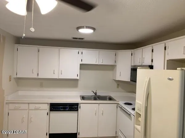 a kitchen with stainless steel appliances a refrigerator a sink and white cabinets
