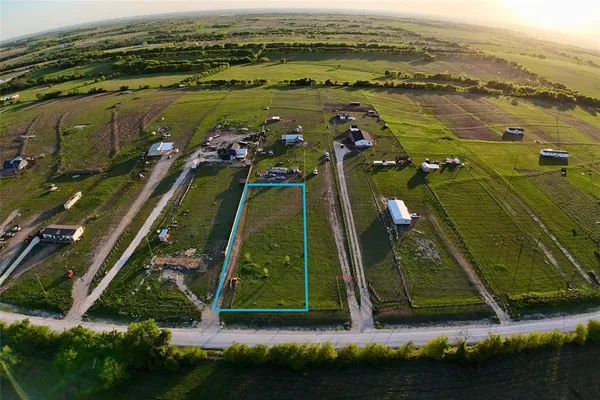 an aerial view of a residential houses with outdoor space and trees