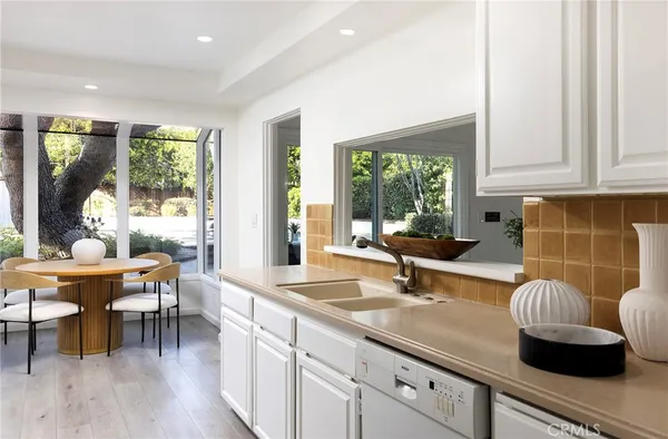 a kitchen with granite countertop a sink a stove and white cabinets with wooden floor