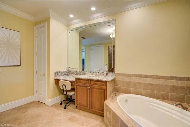 a bathroom with a granite countertop double vanity sink a mirror and a bathtub