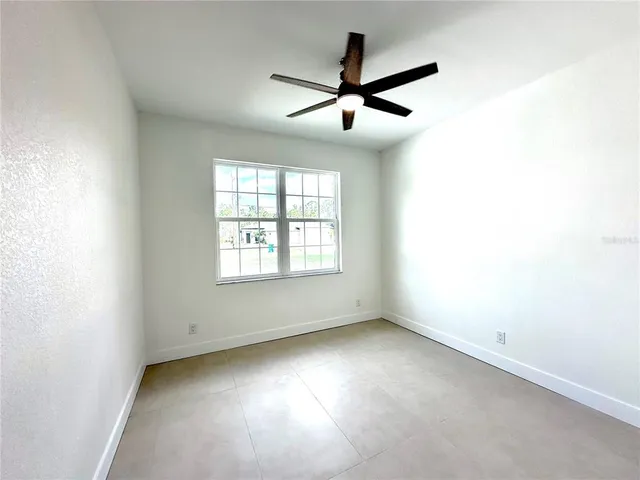 an empty room with ceiling fan and windows