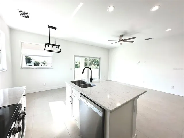 a kitchen with stainless steel appliances a sink a microwave a refrigerator and grey cabinets