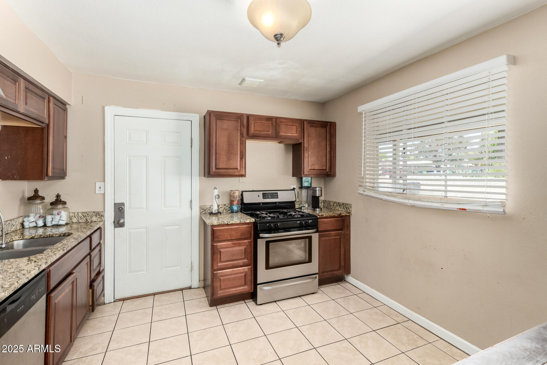 3152 North 24th Drive Phoenix, AZ 85015 - Photo 11 of 28 a kitchen with stainless steel appliances granite countertop a stove a sink and a microwave