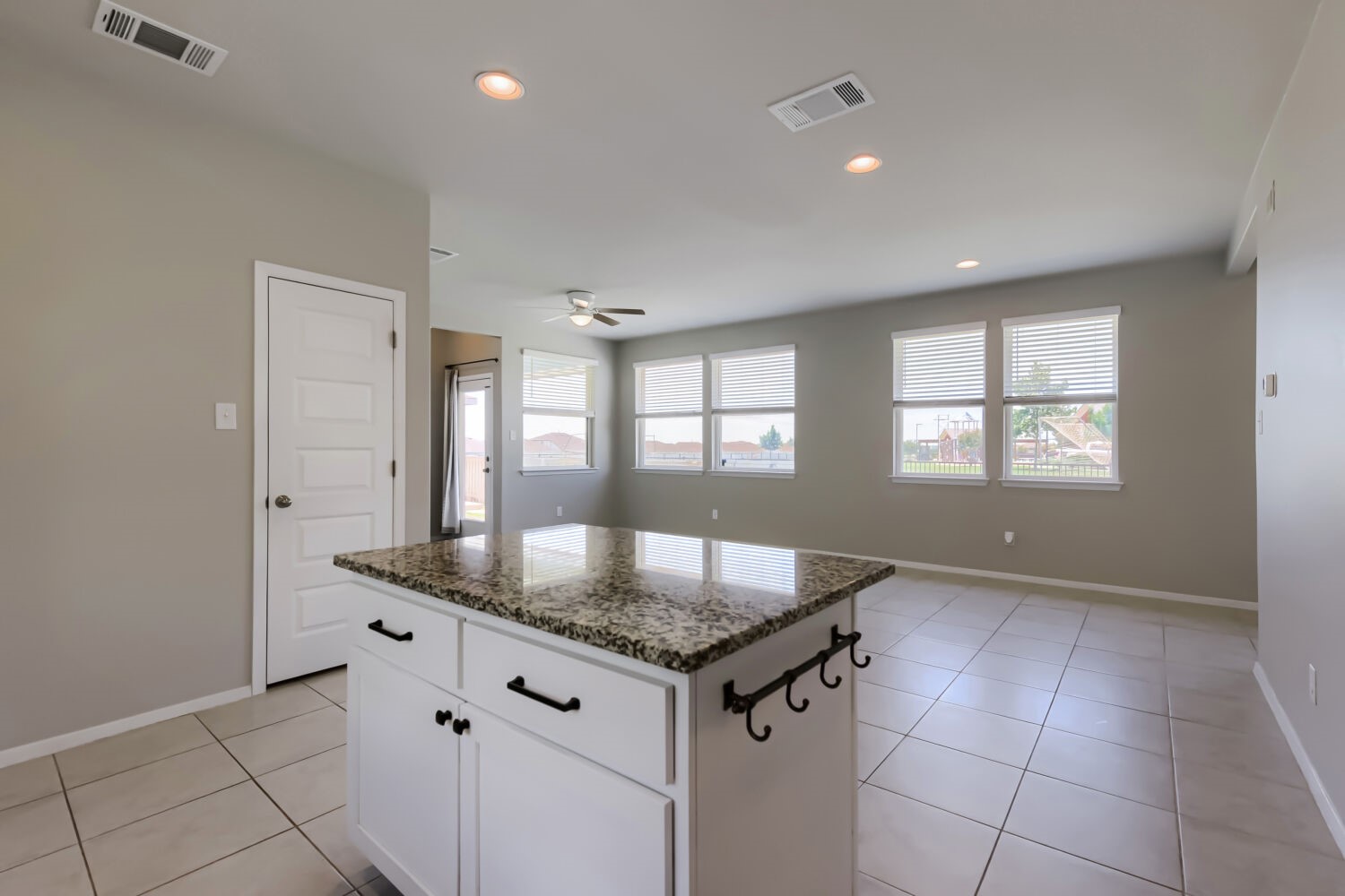 1310 Goforth Road Kyle, TX 78640 - Photo 13 of 24 Kitchen island featuring a granite countertop and white cabinetry with black hardware