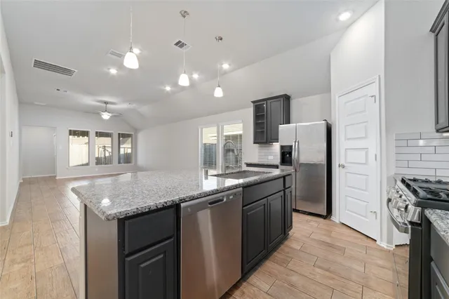 a large kitchen with stainless steel appliances a large counter top a stove a refrigerator and a sink