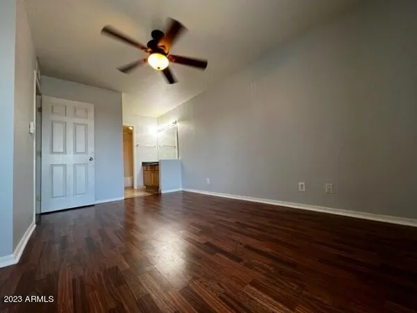 a view of an empty room with wooden floor and a ceiling fan