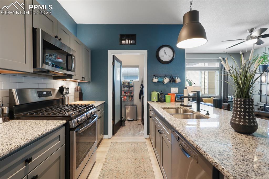 2016 Paddy Grove Colorado Springs, CO 80910 - Photo 13 of 39 a kitchen with stainless steel appliances granite countertop a sink a stove and a wooden cabinets
