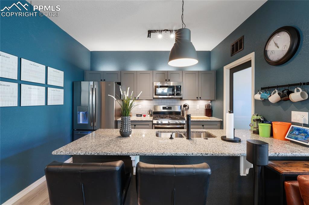 2016 Paddy Grove Colorado Springs, CO 80910 - Photo 15 of 39 a kitchen with stainless steel appliances granite countertop a sink a stove top oven a chimney and a counter top space