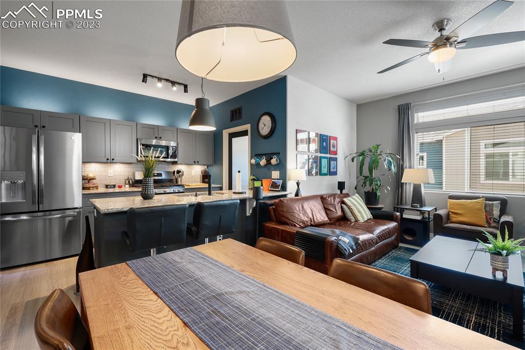 2016 Paddy Grove Colorado Springs, CO 80910 - Photo 17 of 39 a large kitchen with stainless steel appliances kitchen island granite countertop a refrigerator a sink dishwasher a dining table and chairs with wooden floor
