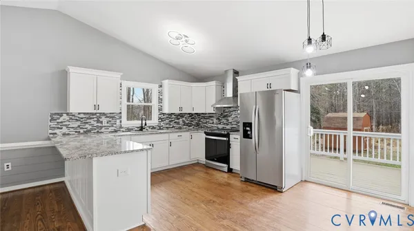 a kitchen with granite countertop a stove a sink and white cabinets with wooden floor