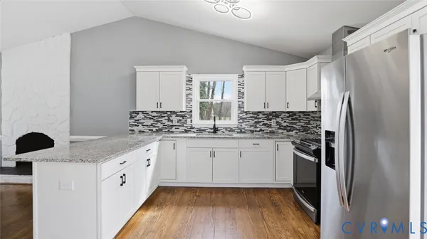a kitchen with granite countertop white cabinets and refrigerator
