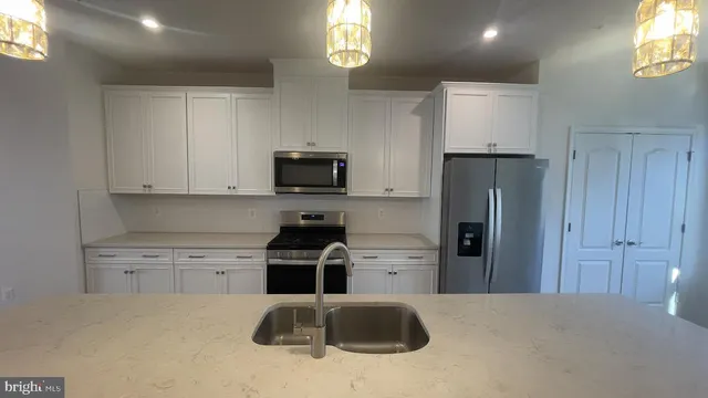 a kitchen with stainless steel appliances a refrigerator a sink a stove and cabinets