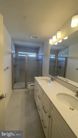 a bathroom with a granite countertop sink a toilet a mirror and shower