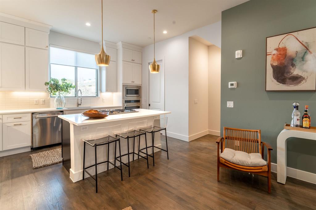 13900 Noel Road, Unit 203 Dallas, TX 75240 - Photo 5 of 11 a kitchen with stainless steel appliances granite countertop a sink a stove a refrigerator and a dining table with wooden floor