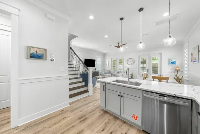 a kitchen with stainless steel appliances granite countertop a sink dishwasher and a refrigerator with wooden floor