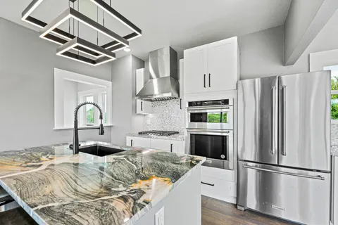 a kitchen with granite countertop a refrigerator and a stove top oven