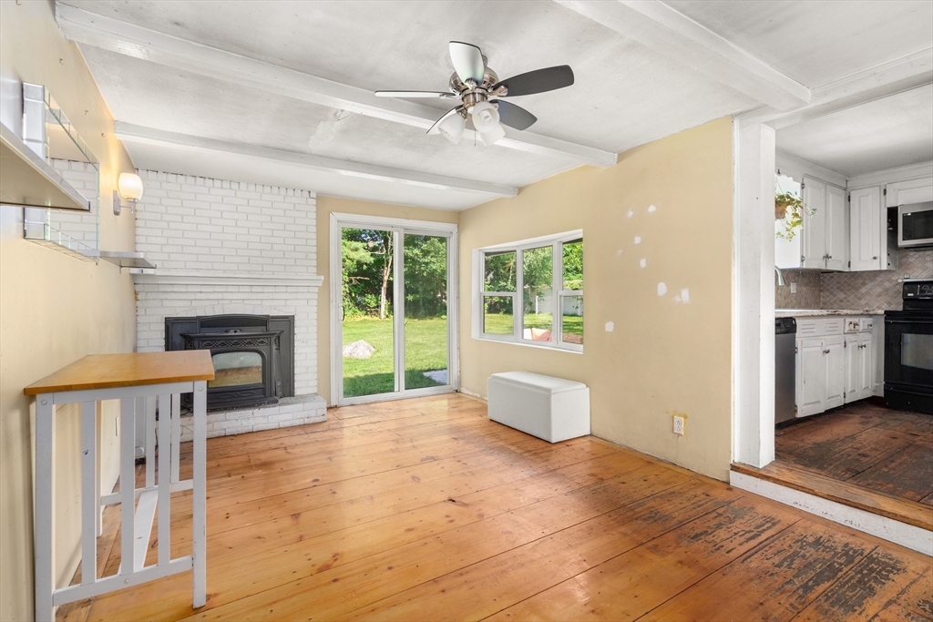 34 Irving Drive Walpole, MA 02081 - Photo 9 of 20 a view of a livingroom with a fireplace a ceiling fan and a kitchen view