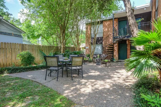 a view of a patio with table and chairs potted plants and large tree