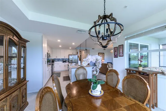 a kitchen with stainless steel appliances kitchen island granite countertop a stove top oven a sink a dining table and chairs with wooden floor