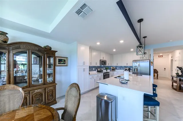 a dining room with stainless steel appliances kitchen island granite countertop a refrigerator and a sink