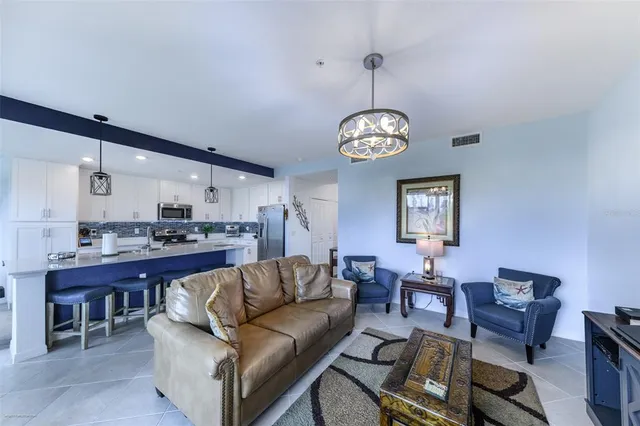a living room with furniture kitchen view and a chandelier