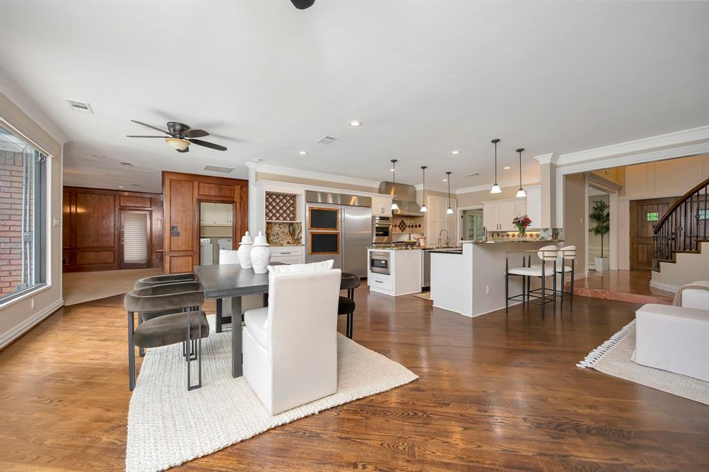 4008 Ramsgate Court Colleyville, TX 76034 - Photo 19 of 33 Spacious kitchen and dining area featuring wood-finish flooring, white cabinetry, integrated stainless steel appliances, a center island with pendant lighting, and a breakfast bar