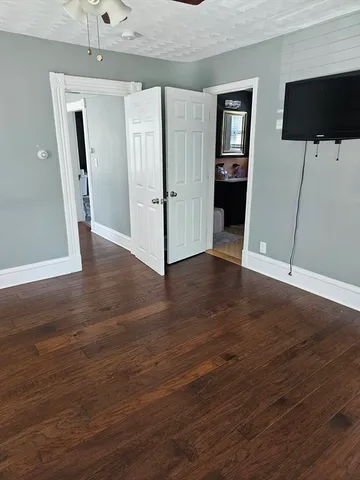 an empty room with wooden floor and a ceiling fan