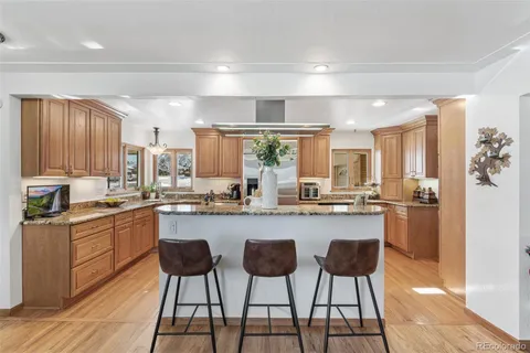 a kitchen with granite countertop wooden floors and wooden cabinets
