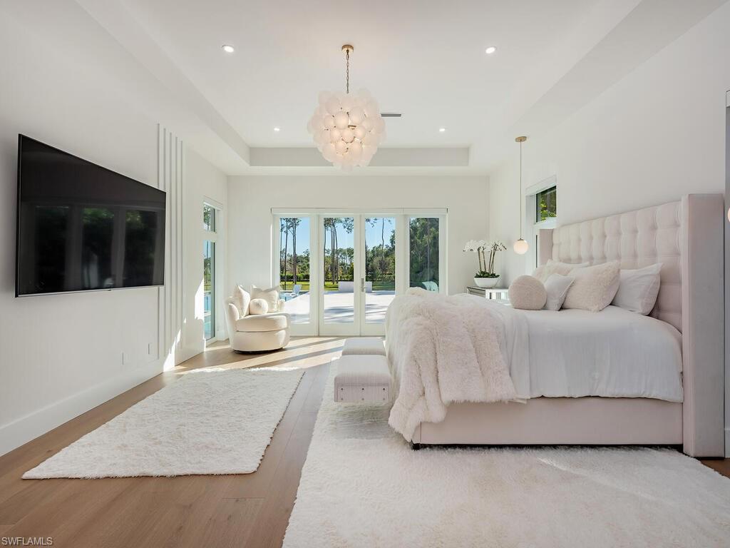 6824 Sable Ridge Lane Naples, FL 34109 - Photo 17 of 36 a spacious bedroom with a large bed and a flat screen tv