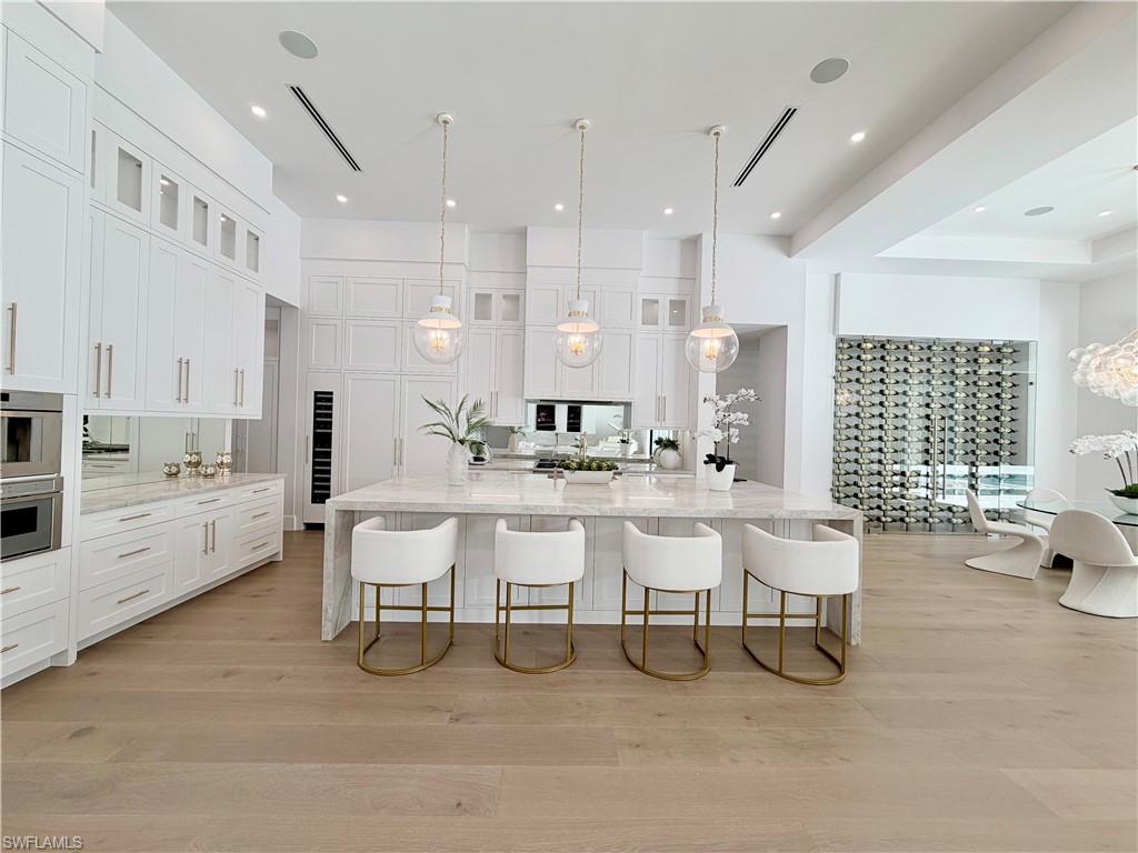 6824 Sable Ridge Lane Naples, FL 34109 - Photo 9 of 36 a large white kitchen with lots of counter space and dining table