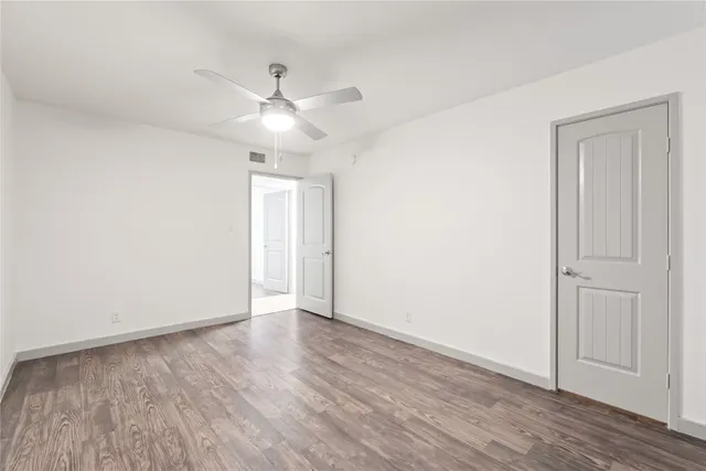 an empty room with wooden floor a ceiling fan and closet