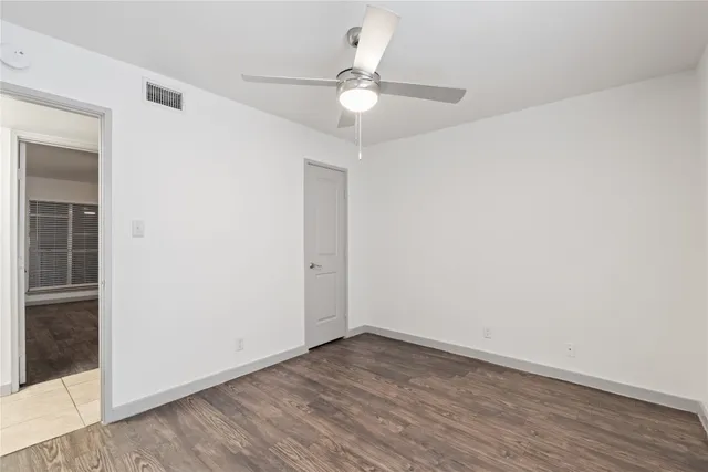 an empty room with wooden floor and fan