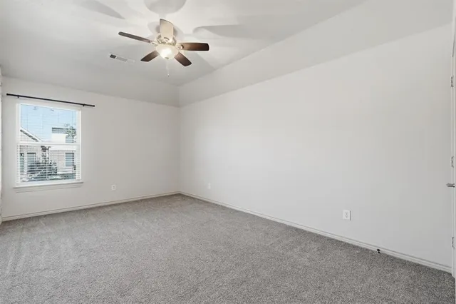 an empty room with ceiling fan and window