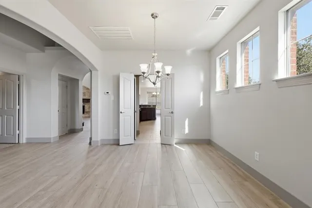 a view of a hallway with wooden floor and a chandelier